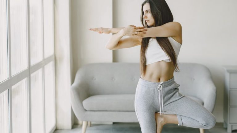 A woman performs a yoga pose at home, focusing on balance and tranquility.